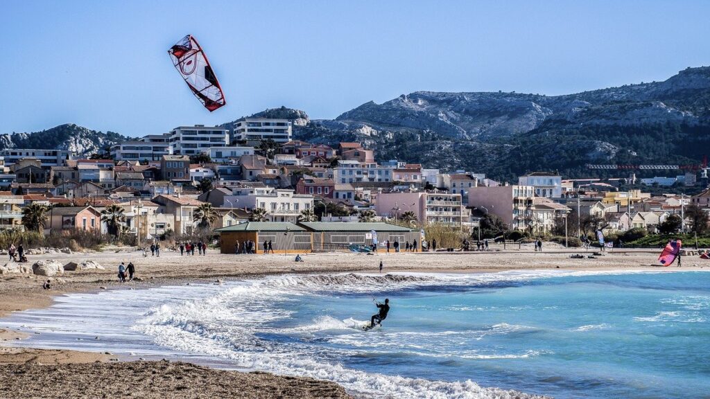 Albanien Ferien an der albanischen Riviera. Das Urlaubsfote zeigt einen Surfer am Strand mit den Bergen im Hitnergrund.